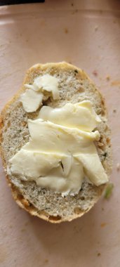 Sandviç yapmak için mükemmel olan kremalı tereyağıyla güzelce yayılmış zanaatkar ekmeğinin yakın plan görüntüsü.