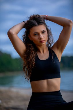 Formda ve enerjik genç bir kadın zarif bir şekilde gücünü ve şık görünümünü sergiliyor.