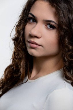 Çarpıcı kıvırcık saçlı ve etkileyici bakışları olan genç bir kadının çarpıcı portresi güçlü bir görsel etki yaratıyor.