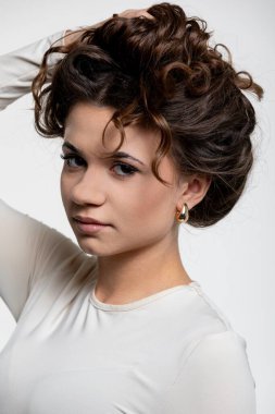 Güzel kıvırcık saç stili ve zarif duruşunu sergileyen bir kadının büyüleyici ve büyüleyici portresi.