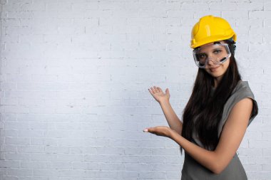 Kendine güveni tam bir kadın, koruyucu gözlük takıyor, boş bir duvarın yanındaki modeller inşaat için mükemmel.