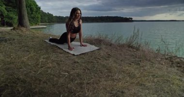 Güzel bir göl kenarında huzurlu bir yoga seansının tadını çıkarın. Doğada mükemmel bir sükunet ve farkındalık sergiliyor.