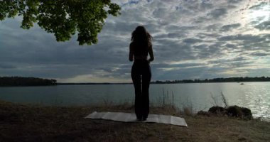 Huzurlu suyun yanında yoga yapan sakin bir figür, huzuru ve doğayla olan bağını derinden somutlaştırıyor.