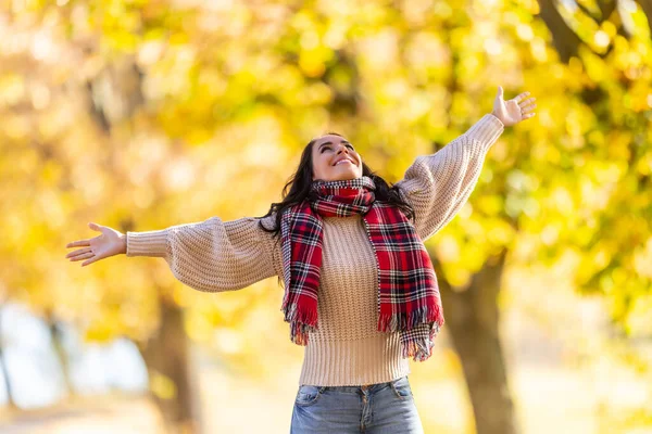 Güzel, genç bir kadın, rengarenk sonbahar havasının tadını çıkarıyor..