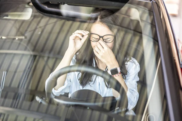 Tired female driver with glasses, needs a break to continue driving the car.