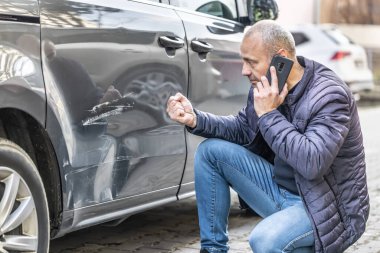 An angry driver calls the insurance company or the police because of a damaged car. clipart