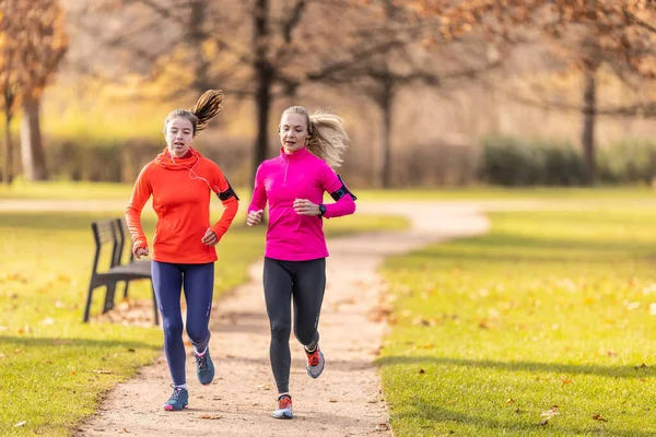 Piękne Dwie Kobiety Biegają Zewnątrz Słonecznym Jesiennym Parku — Zdjęcie stockowe