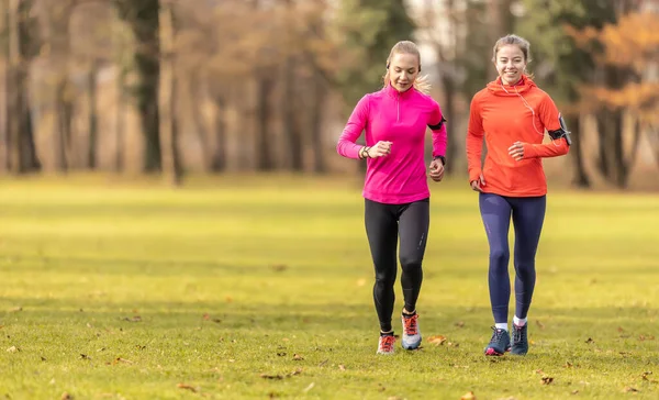 Dwie Młode Kobiety Fitness Biegające Jesiennym Parku — Zdjęcie stockowe