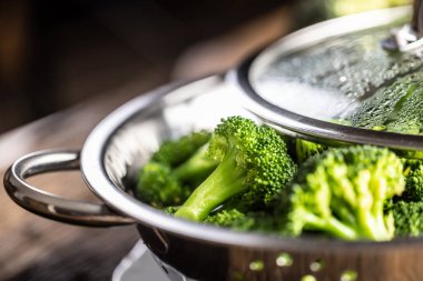 Steamed broccoli in a stainless steel steamer with a lid - Close up. Healthy vegetable concept.