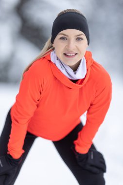 Good looking female trainer in warm clothes during training in winter season. Portrait of a young runner in thermal clothing.
