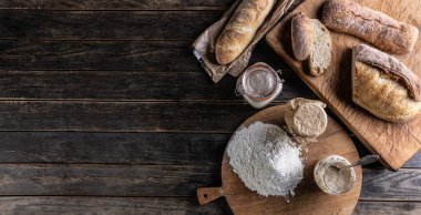 Bakery concept, flour bread and glasses with rye sourdough on the table. - Top of view.
