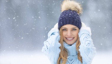 Joy and good mood of a young lady in a winter outfit in a snowy park.