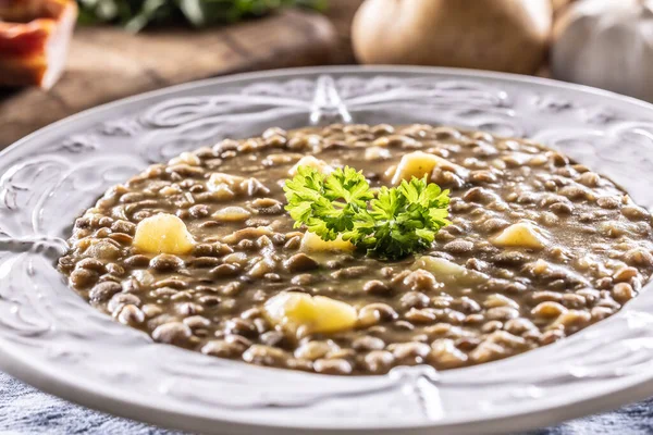 Lentil and potato soup or stew in a rustic plate decorated with parsley.