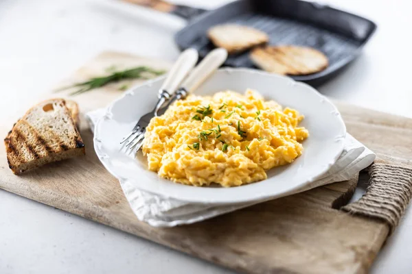 stock image Plate of scrambled organic eggs served with bread toasted on a griddle pan.