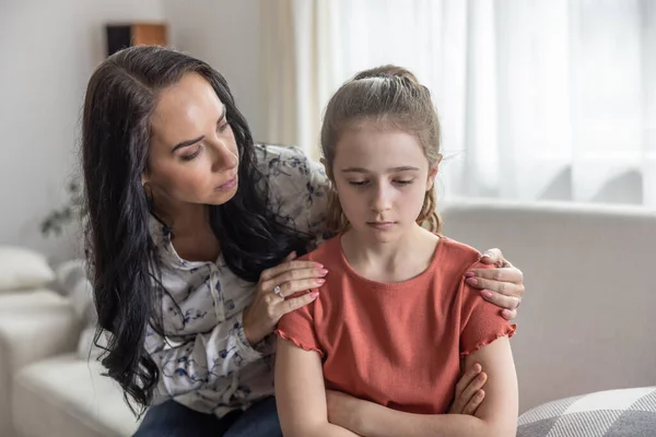 stock image Mother comforts upset daughter that sits with arms crossed on a couch.