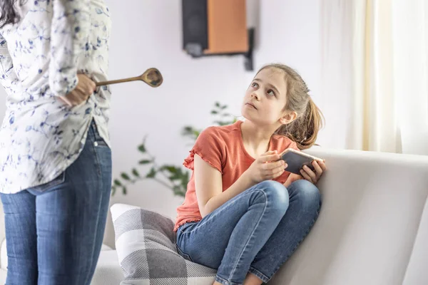 Mother-daughter disagreement with strict mother telling girl off for being online all the time.