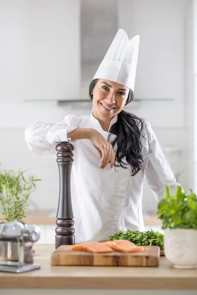 职业女性厨师自信地依靠配料的胡椒研磨机在她面前做饭 — 图库照片