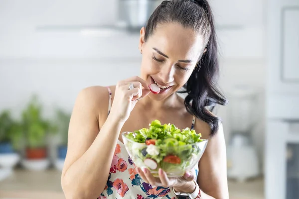 健康的生活方式年轻女人吃生菜沙拉 年轻的黑头发姑娘在厨房里吃着健康的食物 — 图库照片