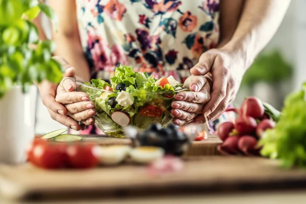 Stock image A man and a woman prepared a healthy spring salad. Together they hold a bowl of healthy food with their hands.