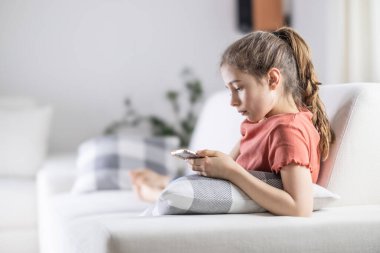 Genç kız evde rahat vakit geçirirken telefonuna bakıyor..