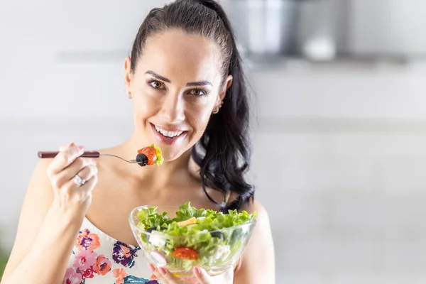 健康的生活方式年轻女人吃生菜沙拉 年轻的黑头发姑娘在厨房里吃着健康的食物 — 图库照片