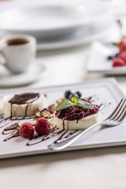 Kahveli bir kafede servis edilen orman meyveli ve çikolatalı panna cotta..