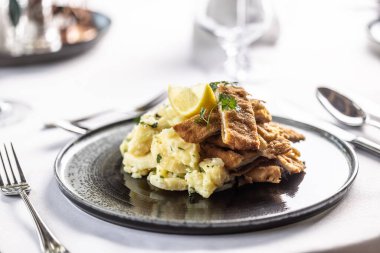 Orecchio d 'elefante dilimlere bölünmüş ve limon dilimli patates salatasında servis ediliyor..