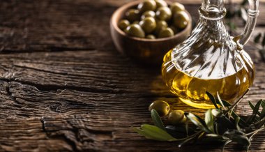 Cam zeytin yağı şişesi ve zeytinli yapraklar ahşap masa üzerine dizayn edilir..