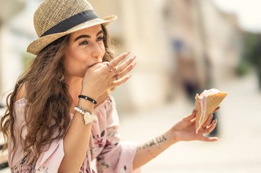 Güzel genç bir bayan sıcak bir yaz gününde erimiş dondurmadan parmaklarını yalıyor..