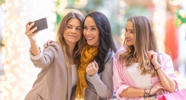 Üç arkadaş Noel alışverişinden sonra süpermarkette selfie çekiyorlar..