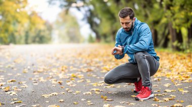 İyi görünümlü bir atlet koşmadan önce spor saatini takar. Boşluğu sol tarafa kopyala.