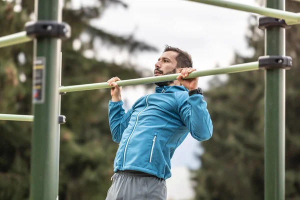 Stock image Young man working out calisthenics in an outdoor gym using parallel bars. He does push-ups on the bar. Concept of healthy lifestyle.