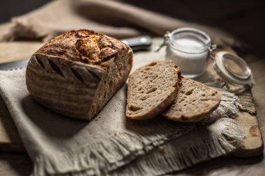 Taze ekşi ekmek, dilimlenmiş ekmek ve kesme tahtasında tuz..