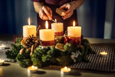 Bir kadın Noel arifesinde bir çelengin son dördüncü mumunu yakıyor..