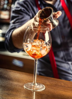 Bardaki barmen yaz kokteyli hazırlıyor. Spritz Veneziano, Aperol likörünü buzlu bardağa dolduruyor..