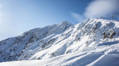 Alçak Tatra 'nın karla kaplı tepelerinin manzarası Jasna ve kayakçıları Chopok dağına götüren teleferik..