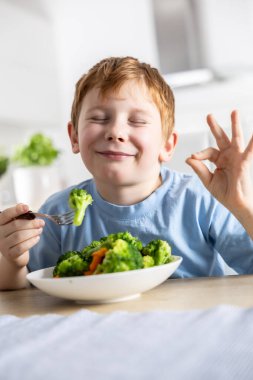 Küçük tatlı bir çocuk öğle yemeğinde brokoli yiyor ve onu çok seviyor..