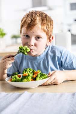 Küçük bir çocuk öğle yemeği yiyor ve brokoli yiyor..