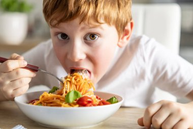 Evdeki mutfakta öğle yemeğinde spagetti yiyen tatlı küçük çocuk..