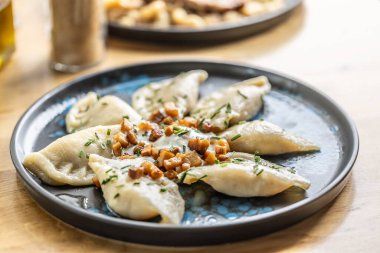 Kızarmış domuz pastırması, taze soğan ve ekşi kremayla servis edilen pirohy tabağı..