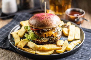 Biftek burger, patates kızartması ve bira, bir bar veya restoran tabağında..