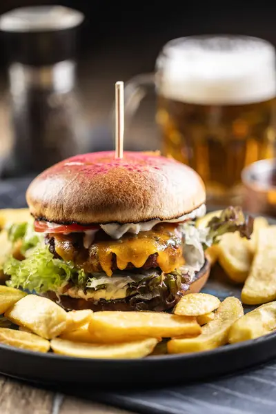 Beef burger with fries and draft beer on a pub or restaurant plate.
