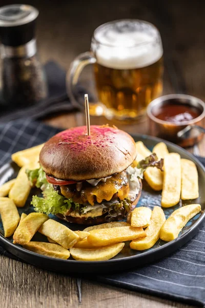 Beef burger with fries and draft beer on a pub or restaurant plate.