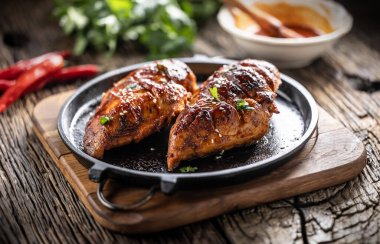 Barbekü soslu marine edilmiş tavuk göğsü ve dökme demir bir tavada servis ediliyor..