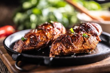 Barbekü soslu marine edilmiş tavuk göğsü ve dökme demir bir tavada servis ediliyor..