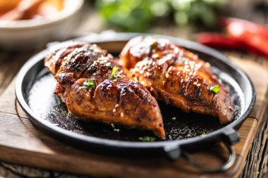 Barbekü soslu marine edilmiş tavuk göğsü ve dökme demir bir tavada servis ediliyor..