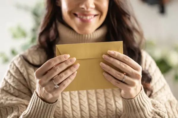 笑顔の若い女性は彼女の手でリサイクル紙で作られた郵便封筒を持っています ストック画像