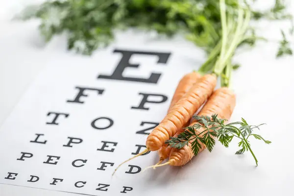 Fresh carrots as a source of vitamin A placed on the eye test chart.
