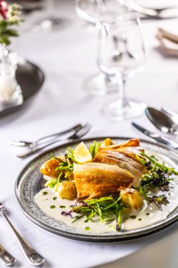 Hafif tütsülenmiş alabalık filetosu, fırında patates, beurre blanc sosu, pırasa ve limon sosu. Restoranda tabakta yaratıcı bir şekilde servis edilen balık..