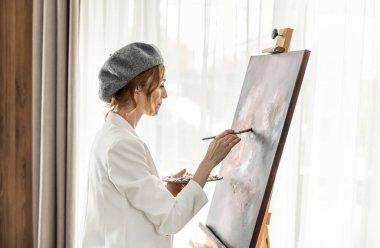 Güzel bayan ressam, resim stüdyosunda resim yaparken eğleniyor. Kadın Sanatçı Sanat Stüdyosunda Soyut Akrilik Resim Üzerinde Çalışıyor.